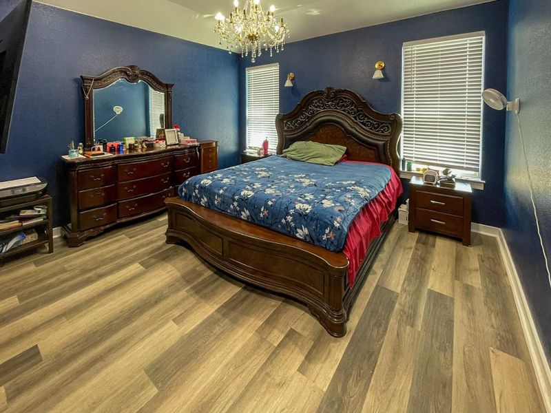 Bedroom featuring wood finished floors, a chandelier, and a textured wall
