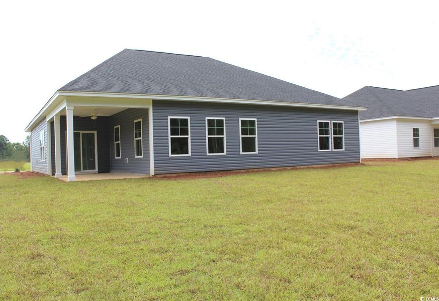 Back of house with a patio, a lawn, roof with shingles, and a ceiling fan Back of house with a patio, a lawn, roof with shingles, and a ceiling fan