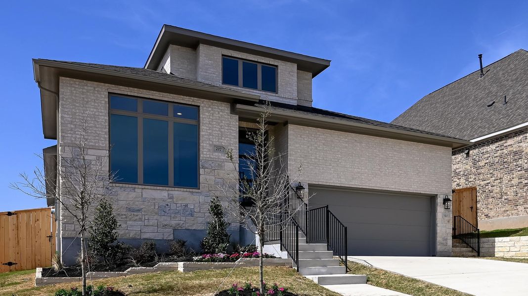 View of front of house with concrete driveway, fence, an attached garage, stone siding, and brick siding View of front of house with concrete driveway, fence, an attached garage, stone siding, and brick siding