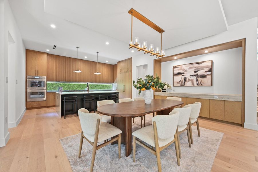 Dining area with light wood finished floors, recessed lighting, and a chandelier