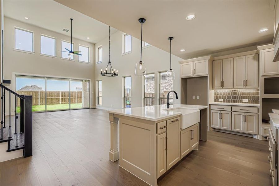 Kitchen with a center island with sink, open floor plan, dark wood-style flooring, recessed lighting, and hanging light fixtures