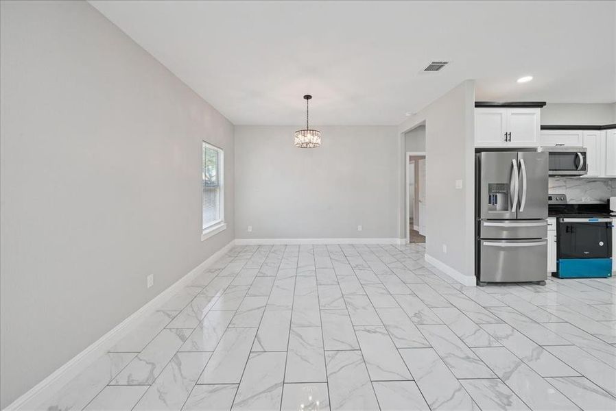 Kitchen with appliances with stainless steel finishes, white cabinetry, a chandelier, light marble finish floors, and recessed lighting