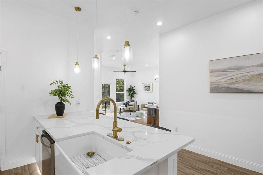 Kitchen featuring light stone countertops, white cabinetry, dark wood-type flooring, a peninsula, and pendant lighting Kitchen featuring light stone countertops, white cabinetry, dark wood-type flooring, a peninsula, and pendant lighting