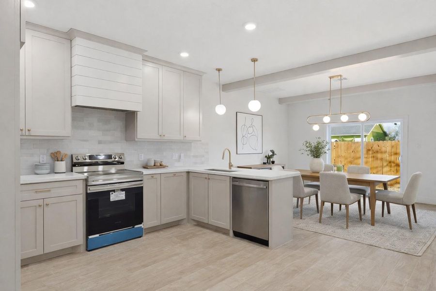 The kitchen/dining room showcases a spacious undermount sink, beams, a custom vent hood and a neutral color palette with elegant gold accents. (staged)