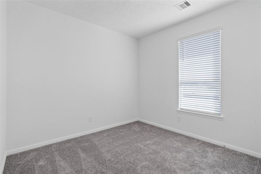 Tucked peacefully in the front of the home is this secondary bedroom. It features plush carpet flooring, large window with blinds, and closet space.