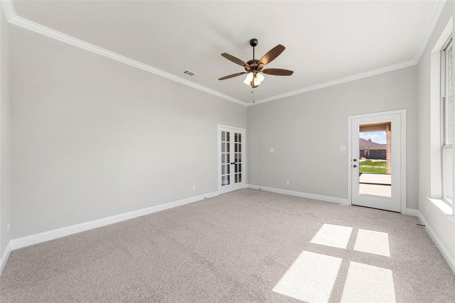 Empty room featuring crown molding, light carpet, a ceiling fan, and baseboards Empty room featuring crown molding, light carpet, a ceiling fan, and baseboards