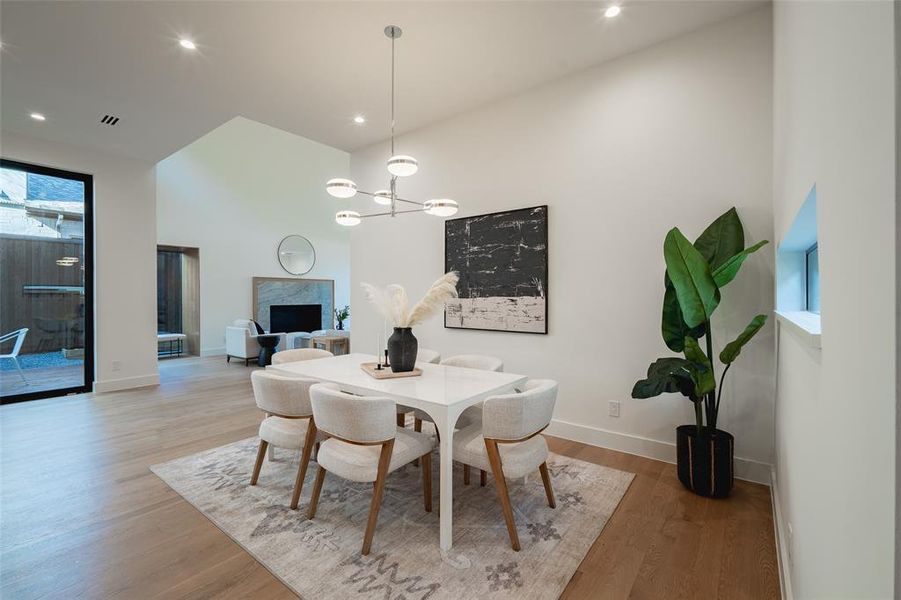 Dining room with an inviting chandelier, a fireplace, and light hardwood / wood-style flooring