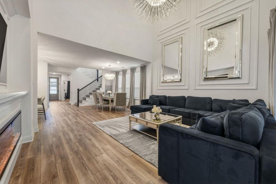 Open-concept living space featuring a wall-mounted fireplace, and tall ceilings with decorative wall molding