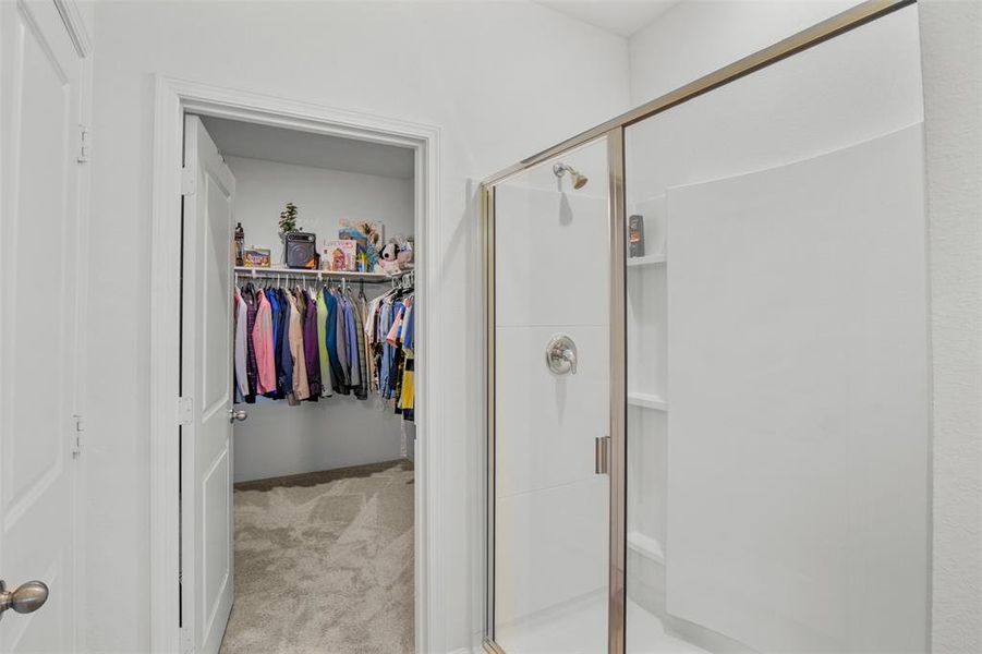 Primary bathroom featuring a shower stall and a spacious closet