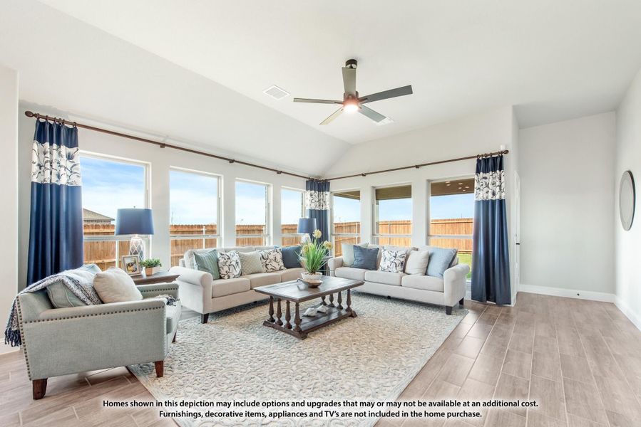 Living room with vaulted ceiling, ceiling fan, large windows, and two sofas on a patterned area rug over wood-look floors