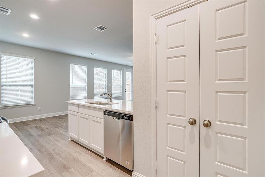 Kitchen featuring dishwasher, sink, white cabinets, and light wood-type flooring