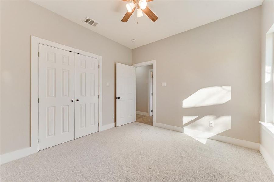 Unfurnished bedroom featuring ceiling fan, light carpet, and a closet