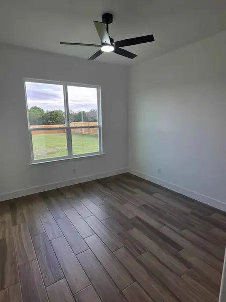 Spare room featuring dark wood-style floors and a ceiling fan Spare room featuring dark wood-style floors and a ceiling fan