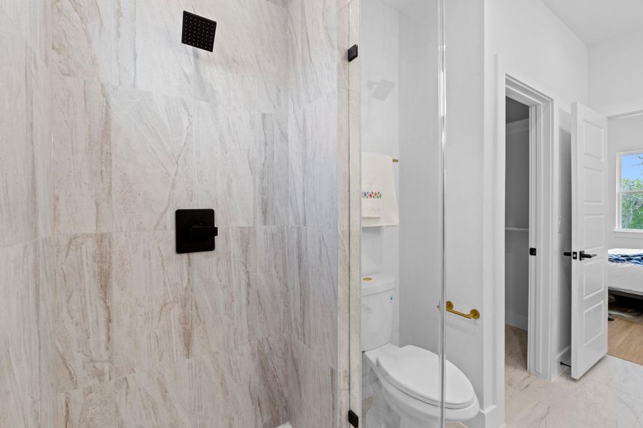 Ensuite bathroom with a marble finish shower and toilet
