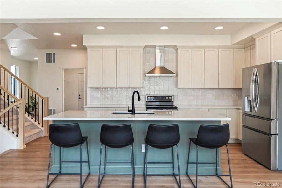 Open-concept kitchen with quartz countertops, oversized island seating, stainless steel appliances, and modern finishes in this Morrison Colorado home