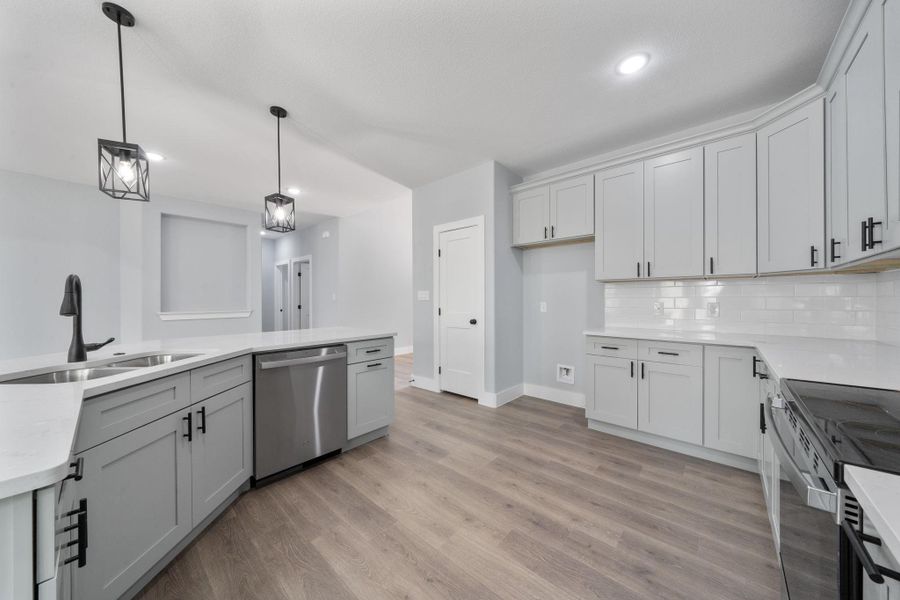 Contemporary kitchen featuring shaker-style cabinetry, white countertops, stainless steel appliances, and wood-finish flooring