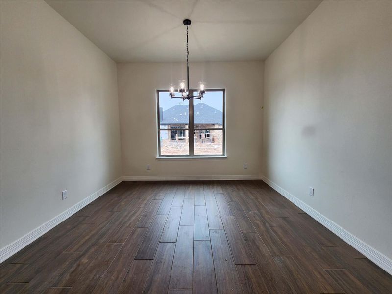 Spacious room featuring wood-finish flooring, neutral-toned walls, and white baseboards