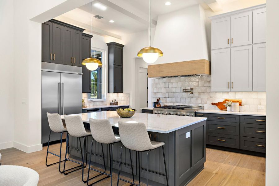 Kitchen featuring built in fridge, stove, visible vents, light wood-type flooring, and custom exhaust hood