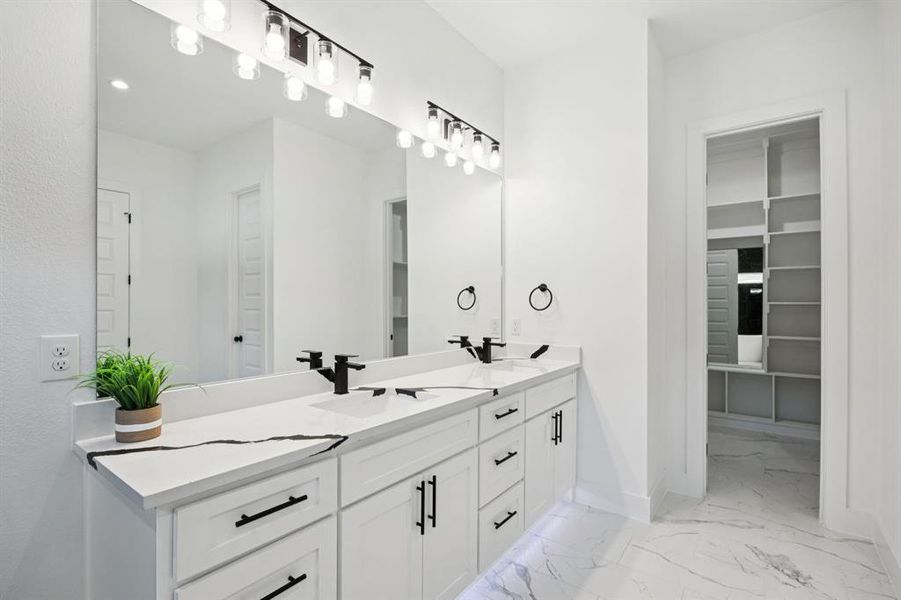 Bathroom featuring double vanity, a walk in closet, and light marble finish floors