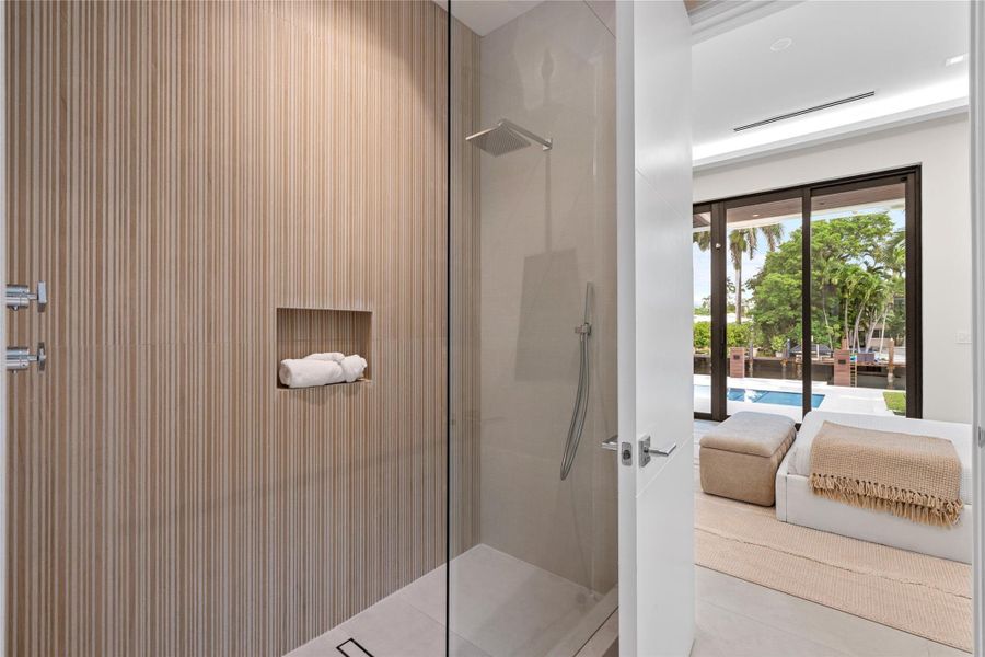 Guest suite with poolside access featuring sliding glass doors, modern ensuite bath, and serene waterfront views. Guest suite with poolside access featuring sliding glass doors, modern ensuite bath, and serene waterfront views.