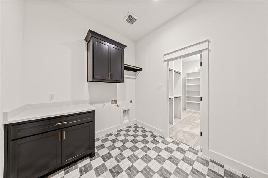 Laundry area featuring checkerboard tile flooring, dark cabinetry, and white countertops