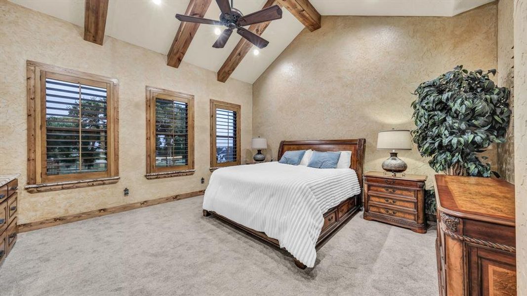 Vaulted ceilings with wood beams and multiple windows with plantation shutters create a bright, airy retreat.