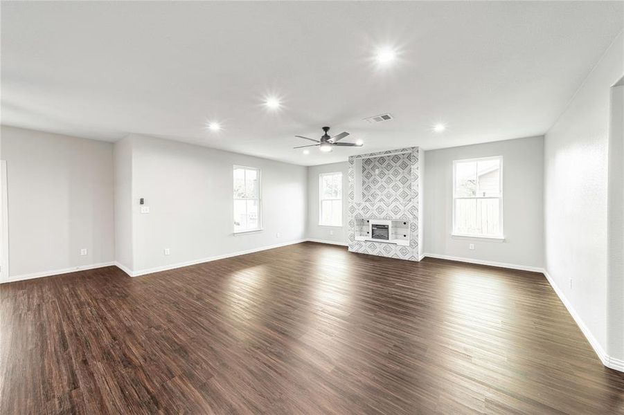 Unfurnished living room with dark wood-style flooring, recessed lighting, healthy amount of natural light, a ceiling fan, and a tiled fireplace
