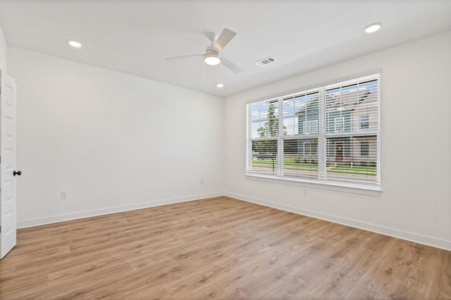 Spacious room featuring wood-finish flooring, a large window with blinds, a ceiling fan, and recessed lighting