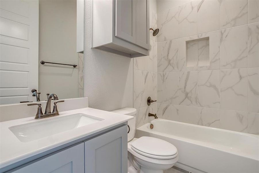 Full bathroom featuring toilet, tiled shower / bath combo, and vanity