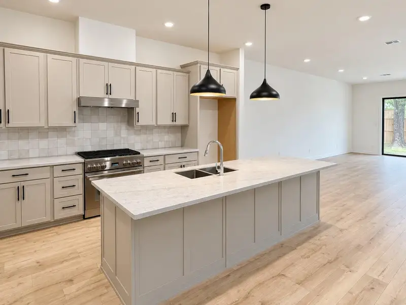 Spacious open-concept kitchen featuring an oversized island, pendant lighting, stainless steel THERMADOR range and Bosch vent hood, ample cabinetry, and modern black hardware. Spacious open-concept kitchen featuring an oversized island, pendant lighting, stainless steel THERMADOR range and Bosch vent hood, ample cabinetry, and modern black hardware.