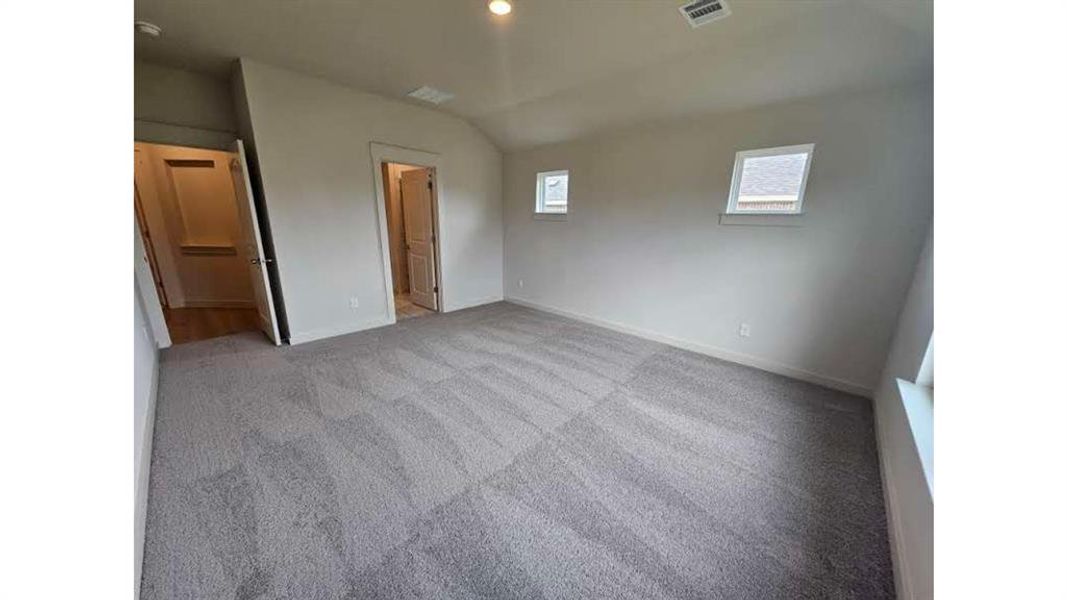 Spacious room featuring neutral carpeting, light-toned walls, and multiple windows Spacious room featuring neutral carpeting, light-toned walls, and multiple windows