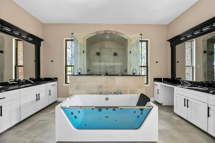 Bathroom with vanity, a wealth of natural light, tile patterned flooring, and a bath