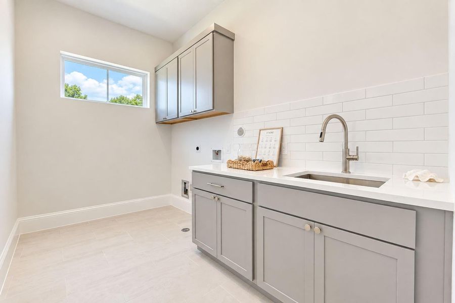Convenient second-floor laundry room thoughtfully located near the bedrooms, featuring generous cabinetry, ample counter space, a utility sink, and natural light. Designed to make everyday routines effortless while providing plenty of workspace and storage. Convenient second-floor laundry room thoughtfully located near the bedrooms, featuring generous cabinetry, ample counter space, a utility sink, and natural light. Designed to make everyday routines effortless while providing plenty of workspace and storage.