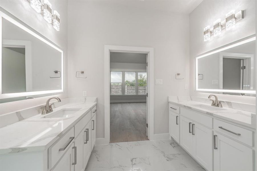 Full bath featuring two vanities and light marble finish floors