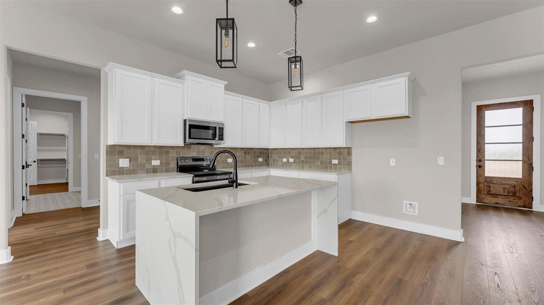 An open kitchen showcases sleek stone countertops alongside warm wood flooring. An open kitchen showcases sleek stone countertops alongside warm wood flooring.