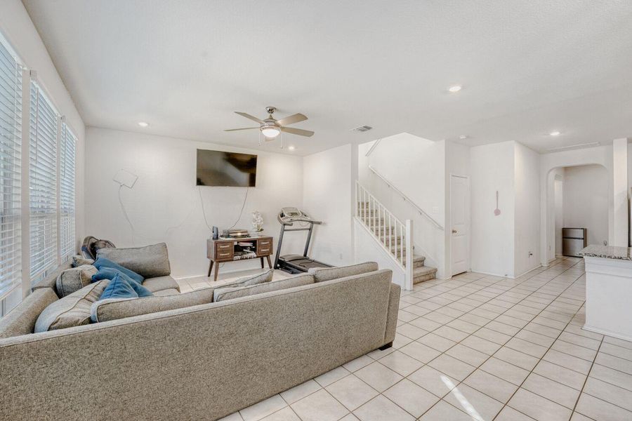 Living area with stairway, light tile patterned floors, ceiling fan, and recessed lighting