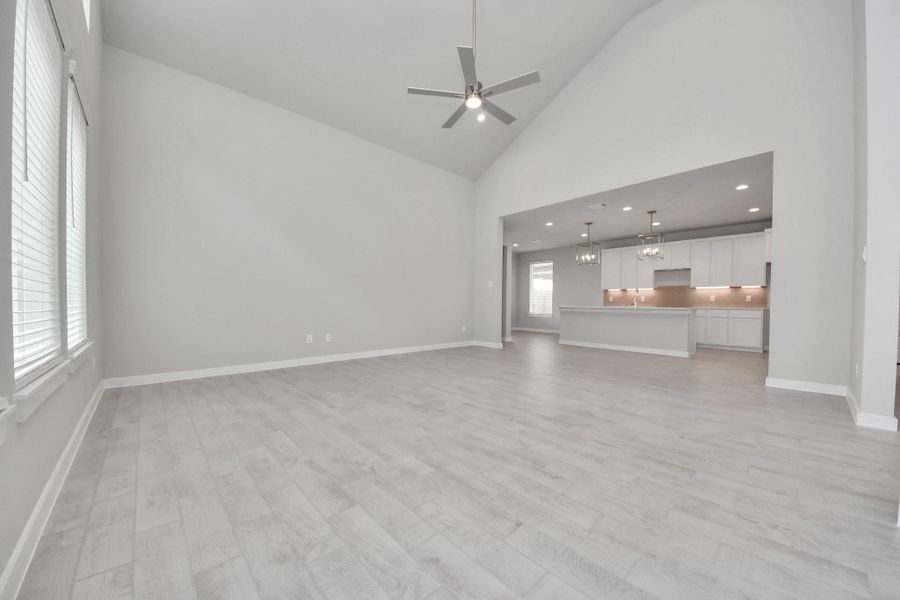 Relax and unwind in this inviting family room, illuminated by abundant natural light streaming in through tall windows, complemented by high ceilings and stunning flooring. Stay comfortable year-round with the gentle breeze from the ceiling fan, creating the perfect atmosphere for family gatherings. Sample photo of completed home with similar floor plan. Actual colors and selections may vary.