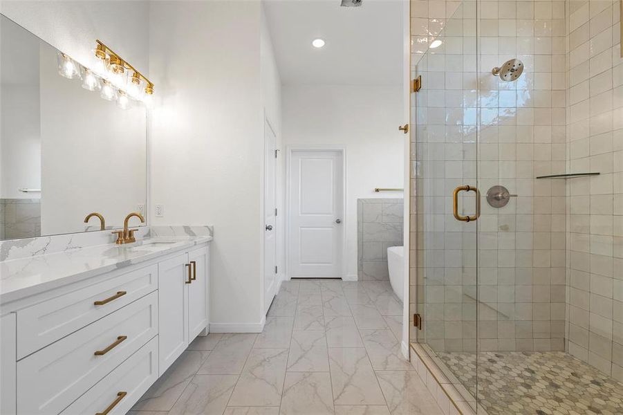 Bathroom featuring a freestanding bath, a stall shower, vanity, recessed lighting, and light marble finish flooring