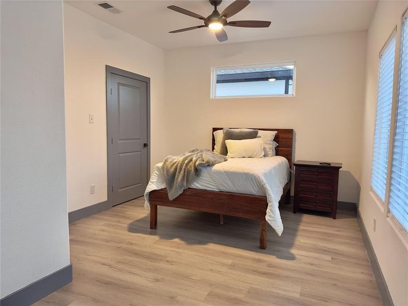 Bedroom featuring multiple windows, light wood-type flooring, and ceiling fan