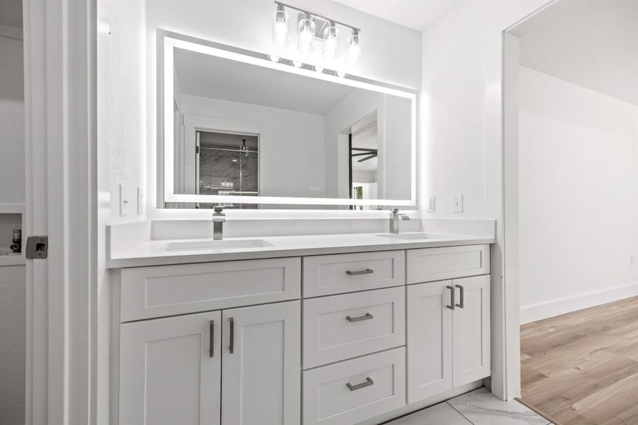 Bathroom featuring a tile shower, double vanity, and light tile  flooring