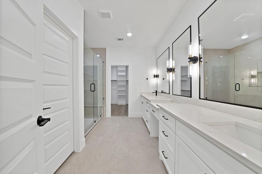 Dual vanities with quartz countertops, custom cabinetry, large framed mirrors, and contemporary sconce lighting Dual vanities with quartz countertops, custom cabinetry, large framed mirrors, and contemporary sconce lighting