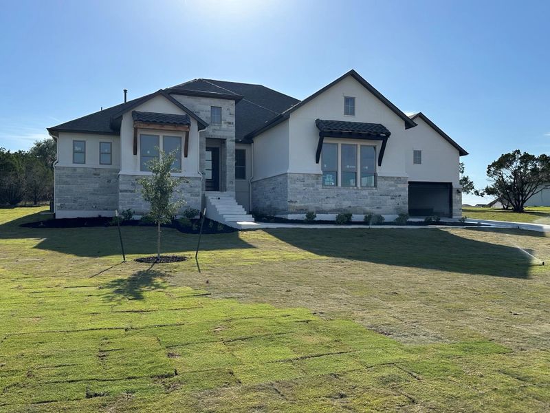 View of front of house featuring stone siding, a front yard, and stucco siding View of front of house featuring stone siding, a front yard, and stucco siding