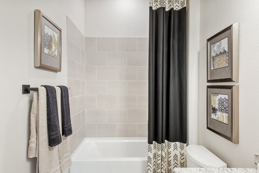 Bathroom with soaking tub, tiled surround, black and white shower curtain, and towel bar with folded towels Bathroom with soaking tub, tiled surround, black and white shower curtain, and towel bar with folded towels