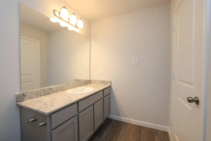 Enjoy the spacious vanity with granite countertops, ample under-sink storage, and modern lighting.