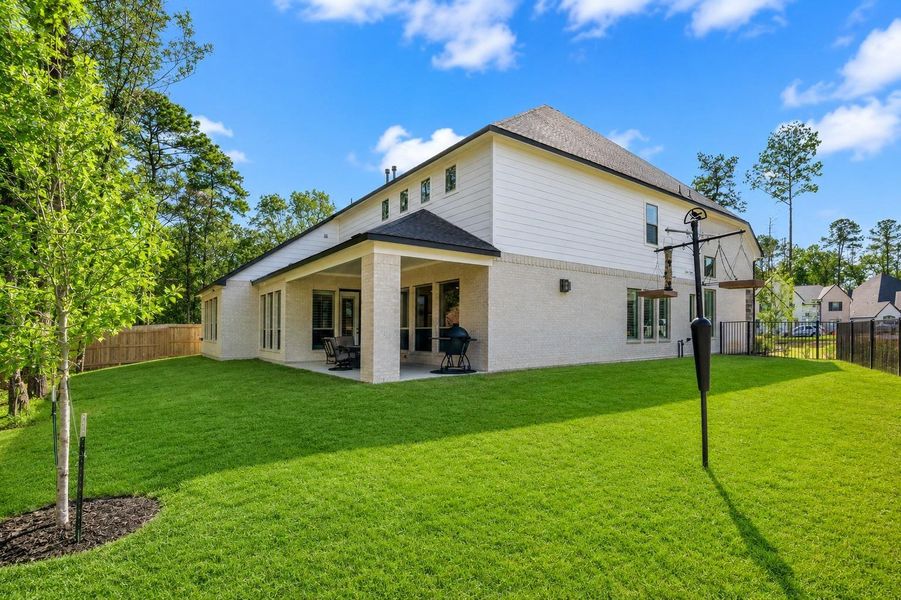 Enjoy a spacious backyard with a covered patio area perfect for outdoor dining. The property is bordered by trees, providing a sense of privacy and a connection to nature.