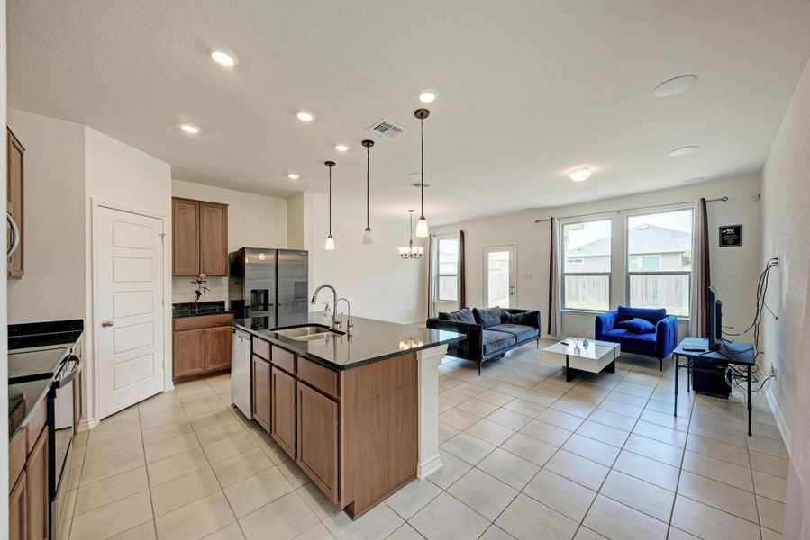 A well-appointed kitchen island with dark countertops overlooks a generous living area, ideal for gathering and entertaining.