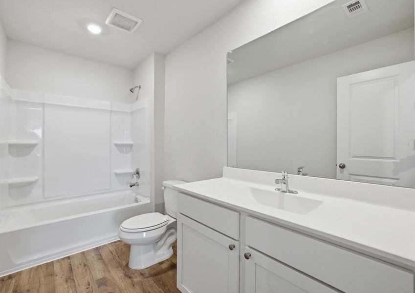 Secondary bathroom featuring a tub/shower combination, a white vanity with cultured marble countertop, and a large mirror.