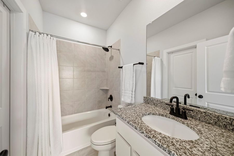 The third bathroom is finished with tile floors, a granite counter and recessed lighting, creating a clean, upscale feel. A tub-and-shower combination with a coordinating tile surround adds both style and functionality.