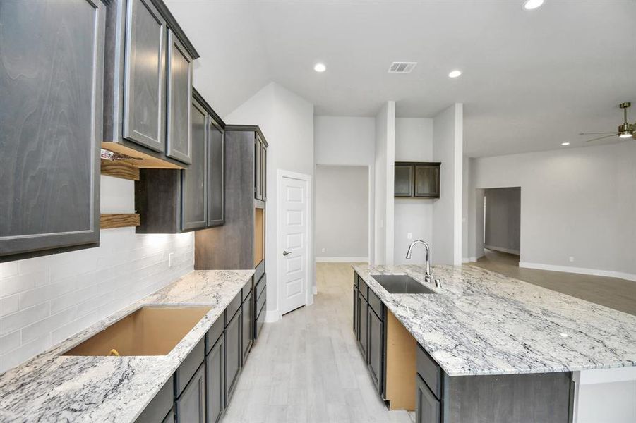 Culinary haven, featuring granite countertops, a tile backsplash, stainless steel appliances (to be installed), and 42” upper cabinets.