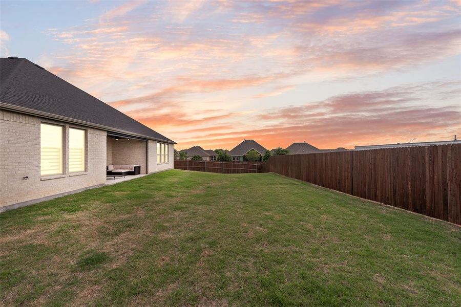 Spacious backyard with a covered patio, extensive lawn area, and a privacy fence